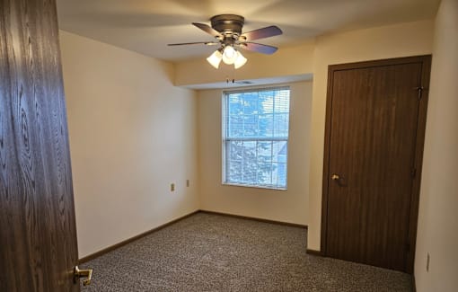 A room with a ceiling fan and a window.