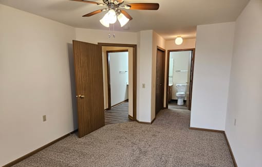 A room with a ceiling fan and carpeted floor.