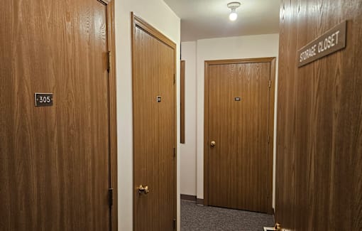 A hallway with doors and a sign that says "Storage Closet".