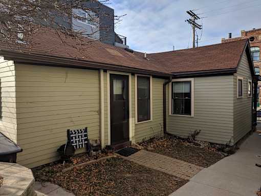 A small house with a brown roof and a grey siding.