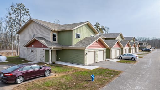 A row of houses with cars parked in front.