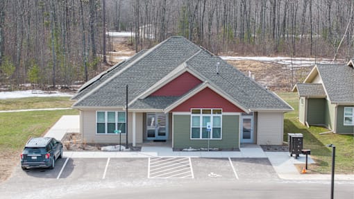 A small building with a red roof is surrounded by a parking lot.