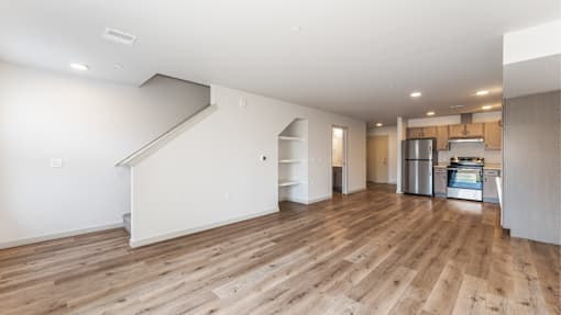A spacious room with wooden flooring and a staircase leading to another level.