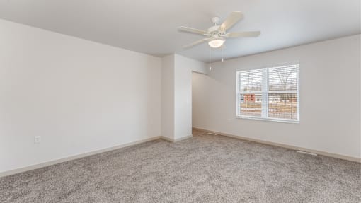 A room with a ceiling fan and a window with blinds.