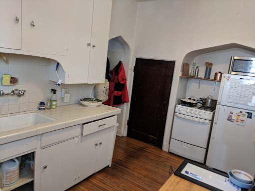A small kitchen with white cabinets and a white fridge.