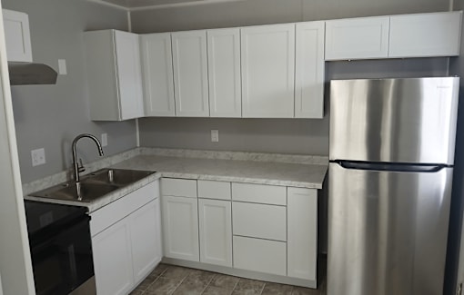 A kitchen with white cabinets and a stainless steel refrigerator.