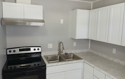 A kitchen with a black stove top oven and white cabinets.