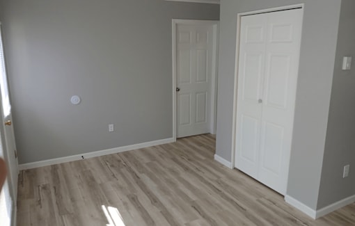 A room with two white doors and wooden flooring.