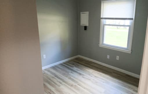 A room with a window and a wooden floor.
