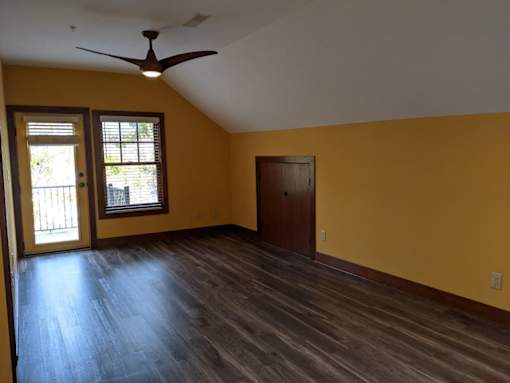 A room with a ceiling fan and sliding glass doors.