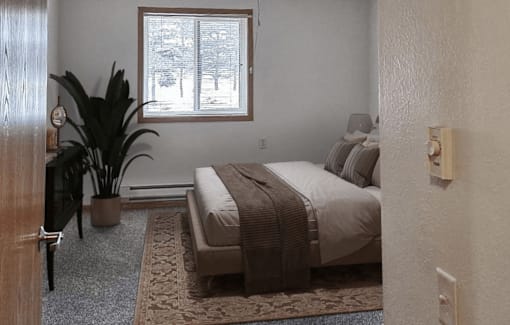 A bedroom with a bed, a potted plant, and a window.