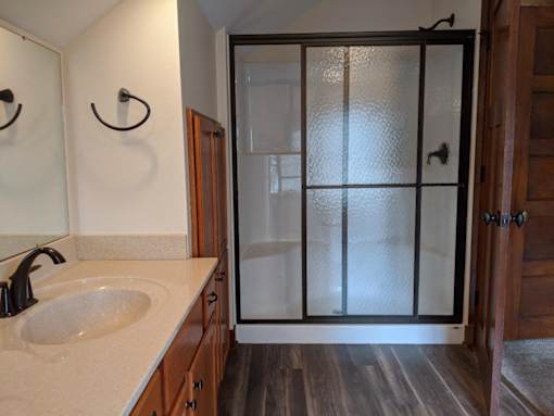 A bathroom with a sink, mirror, and shower door.