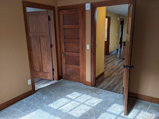 A room with a tan wall and a wooden floor with a carpet.