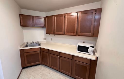 A kitchen with brown cabinets and a white microwave.