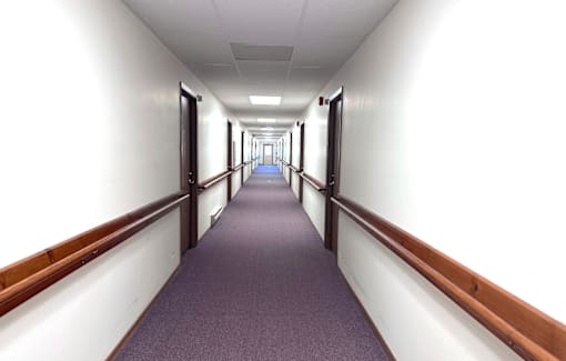 A long hallway with purple carpeting and white walls.