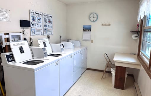 A laundromat with washers and dryers and a clock on the wall.