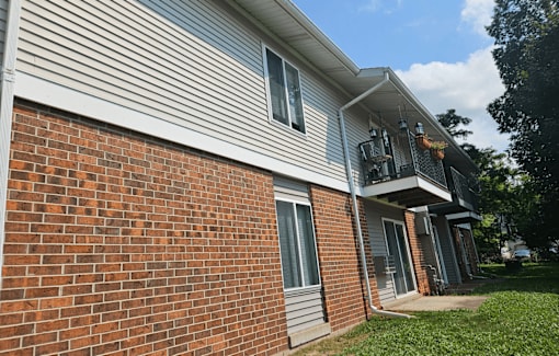 A house with a red brick wall and a grey siding.