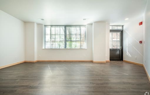 A large empty room with a window and a door.