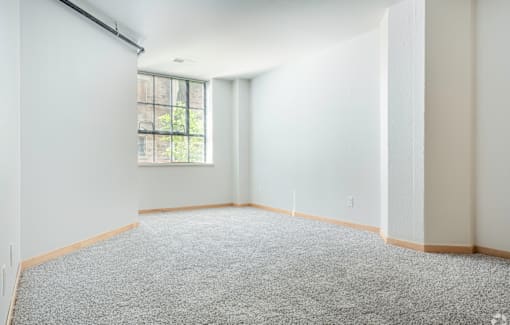 A room with a carpeted floor and a window.