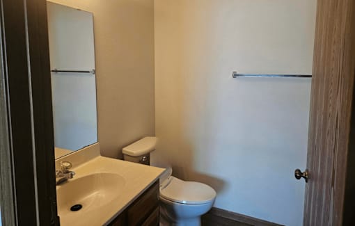 A bathroom with a toilet, sink, and mirror.