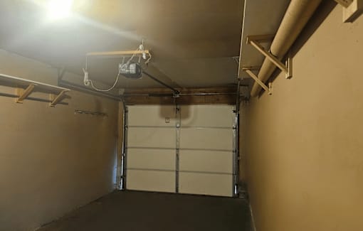 A garage with a white door and a light on the ceiling.