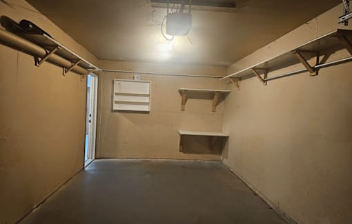A room with a door, a shelf, and a light fixture.