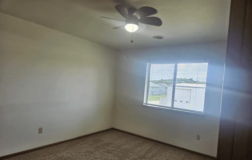 A room with a ceiling fan and a window.