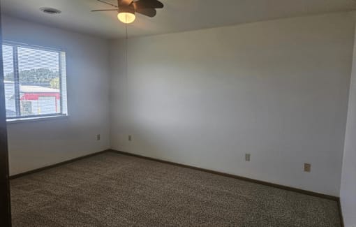 A room with a ceiling fan and carpeted floor.