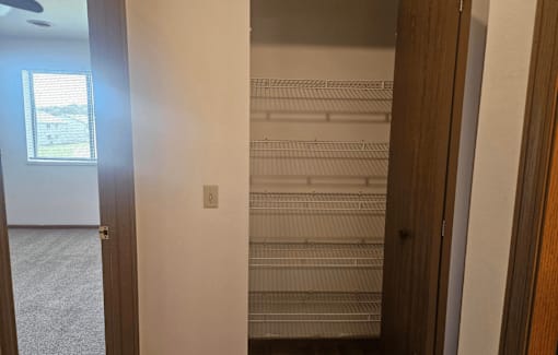 A room with a window and a door leading to a hallway.