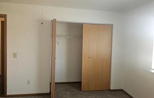 A room with a wooden door and a carpeted floor.