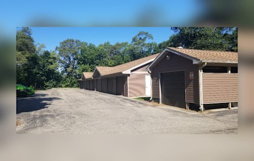 A row of garages are lined up on a gravel lot.