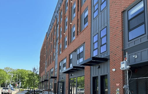 a red brick apartment building with gray and black facade