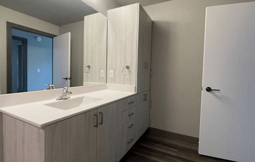 a bathroom with white cabinets and a white sink