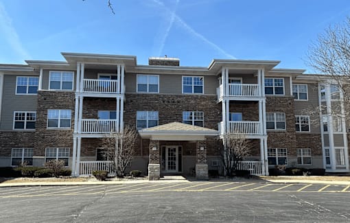 A large apartment building with a parking lot in front.