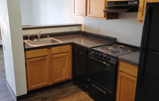 A black stove and oven in a kitchen with wooden cabinets.