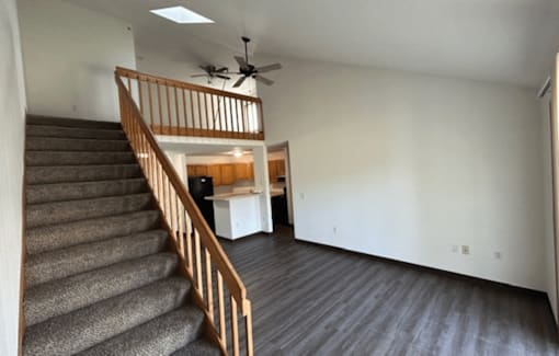 A room with a staircase and a ceiling fan.