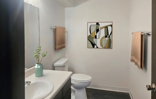 A bathroom with a toilet, sink, and a painting on the wall.