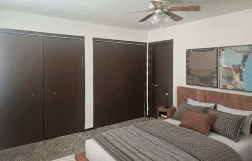 A bedroom with a bed, pillows, and a ceiling fan.