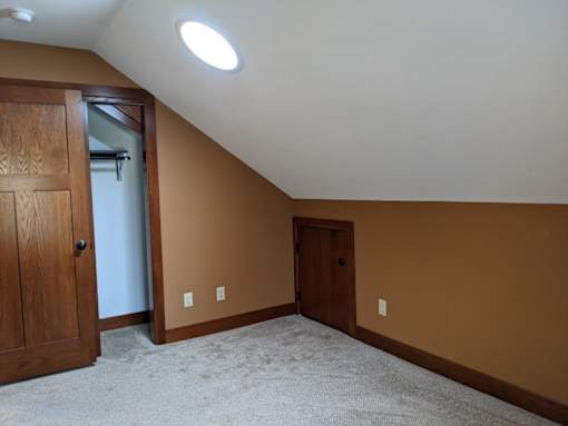 A room with a carpeted floor and two doors.