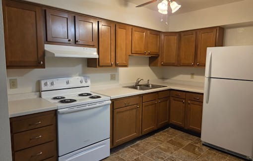 A kitchen with white appliances and brown cabinets.