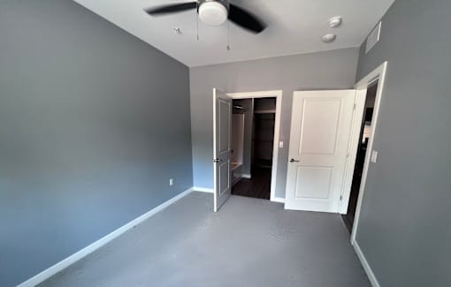 A room with a ceiling fan and two doors.