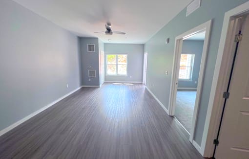 A room with a ceiling fan and wooden flooring.