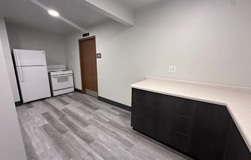 A kitchen area with a white fridge, a white oven, and a wooden door.