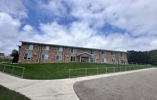 A long building with a grey roof and a white fence in front of it.