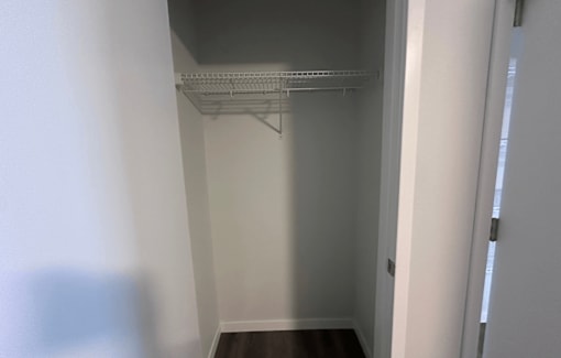 Empty white hallway with a shelf on the wall.