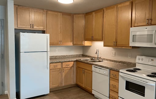 A kitchen with white appliances and wooden cabinets.