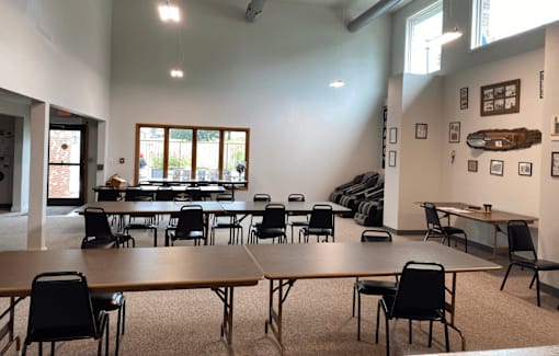 A room with tables and chairs and a window.