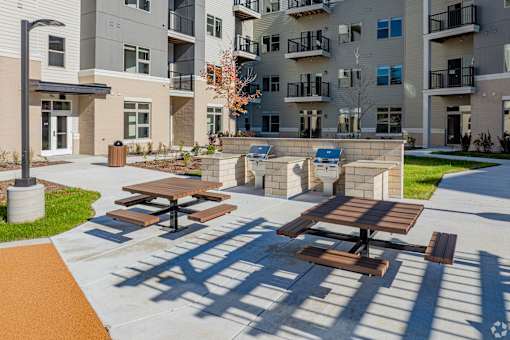 Picnic tables are set up on a patio in front of apartment buildings.
