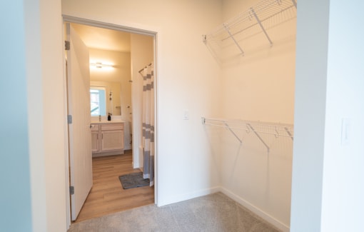 a walk in closet with clothes rails and a bathroom with a sink and a mirror