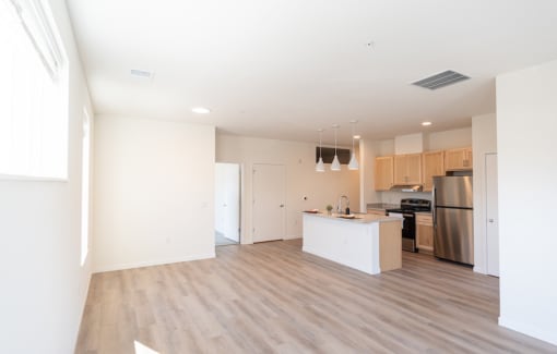 an empty living room and kitchen with white walls and wood floors